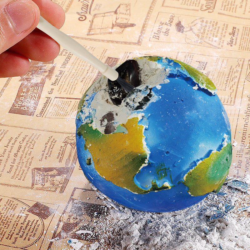 Children's excavation toy set with a planet model, excavation tools, brush, gemstones/fossils, and an educational poster designed for STEM learning