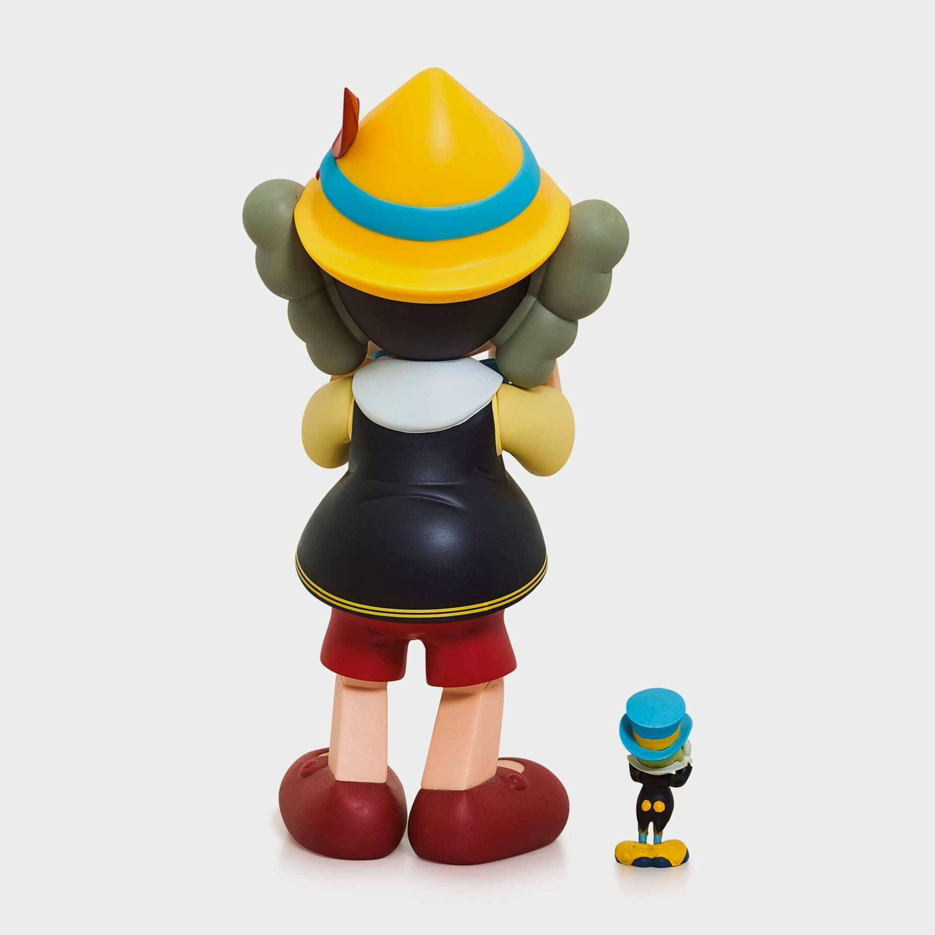 KAWS collectible cast vinyl figure featuring Pinocchio and Jiminy Cricket, limited edition from 2010, measuring 26×12.7×11.4 cm.